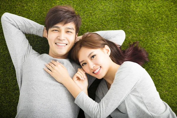 Feliz casal sorridente relaxante na grama verde — Fotografia de Stock