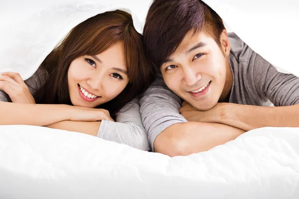 Happy νεαρό ζευγάρι ξαπλωμένο σε ένα κρεβάτι — Φωτογραφία Αρχείου