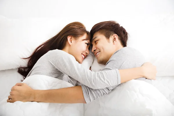 Jovem feliz lindo casal deitado em uma cama — Fotografia de Stock