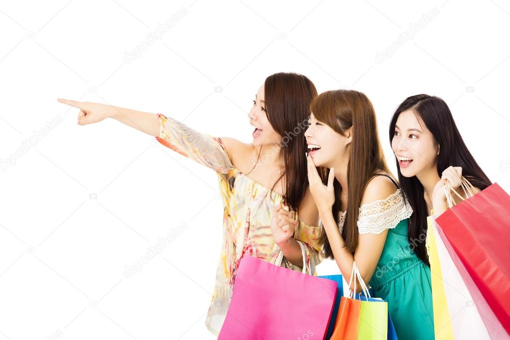 Group of happy young woman with shopping bags looking  something