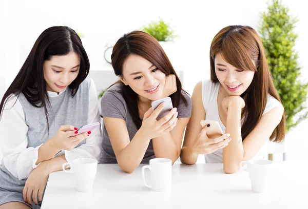 Tres mujeres jóvenes felices viendo el teléfono inteligente en la sala de estar —  Fotos de Stock