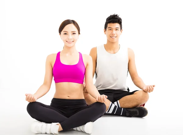 Pareja joven practicando yoga aislado sobre blanco — Foto de Stock