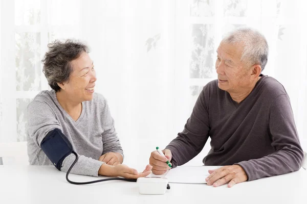 Lyckliga äldre paret tar blodtryck i vardagsrum — Stockfoto
