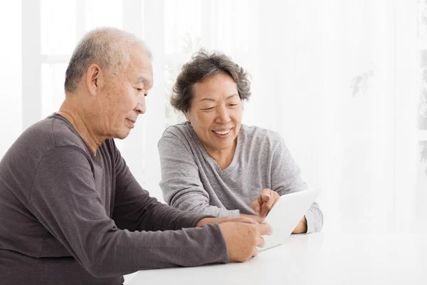 Feliz pareja de ancianos viendo la tableta en la sala de estar — Foto de Stock