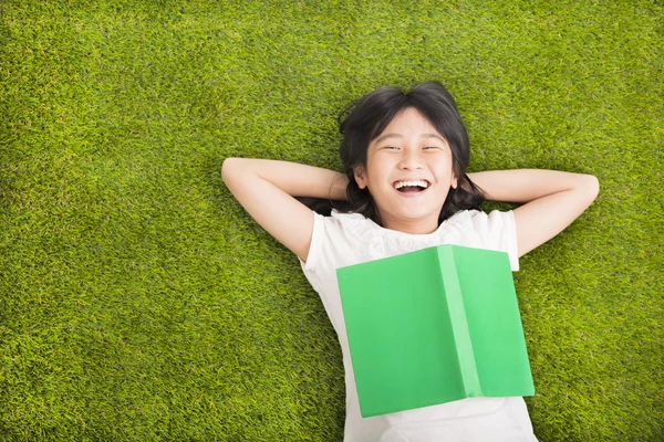 Ευτυχισμένη κοριτσάκι με το βιβλίο και αναπαύεται στο γρασίδι — Φωτογραφία Αρχείου