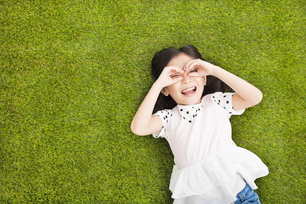 Gelukkig meisje met op zoek gebaar op het gras — Stockfoto