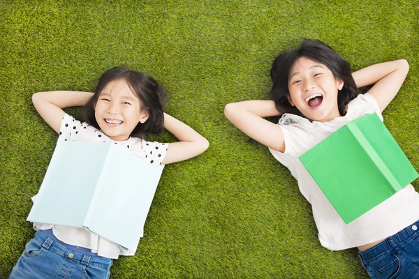 Meninas felizes com livro e descansando na grama — Fotografia de Stock