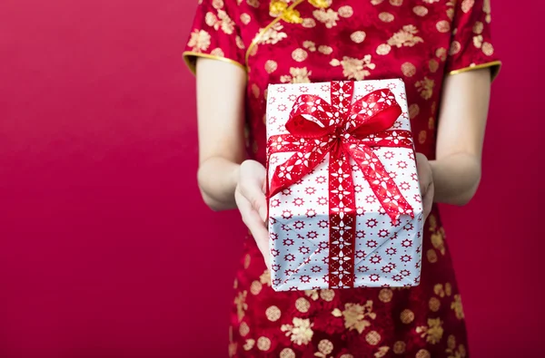 Молодая женщина держит подарочную коробку на красном фоне — стоковое фото