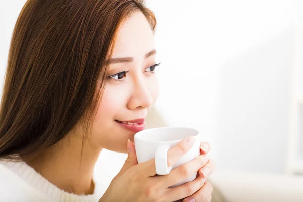 소파에 앉아 커피를 마시는 젊은 여자 — 스톡 사진
