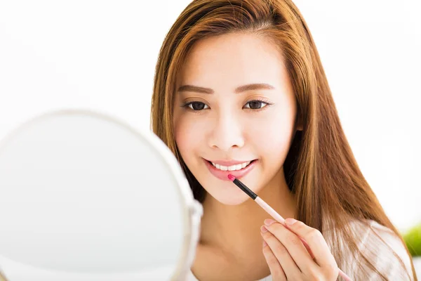 Beautiful young woman putting on red lipstick — Stock Photo, Image