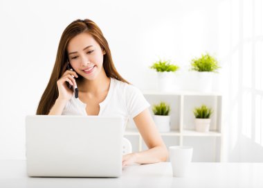 mutlu genç kadın dizüstü bilgisayar ve cep telefonu