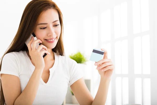 Jovem mulher falando ao telefone e mostrando cartão de crédito — Fotografia de Stock