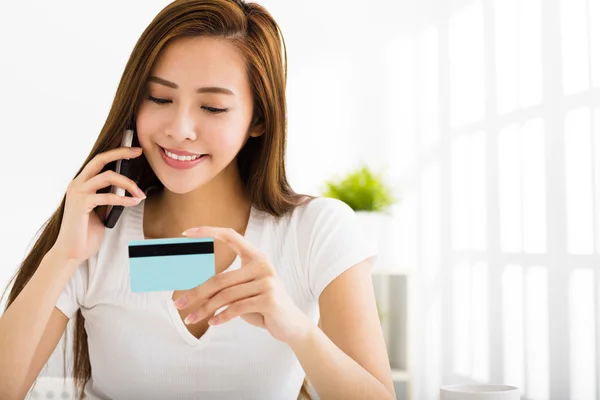 Mujer joven hablando por teléfono y mostrando la tarjeta de crédito — Foto de Stock