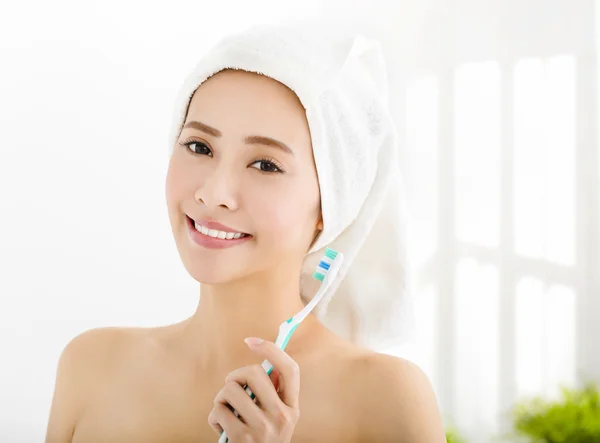 Sorrindo jovem com toalha na cabeça e segurando escova de dentes — Fotografia de Stock