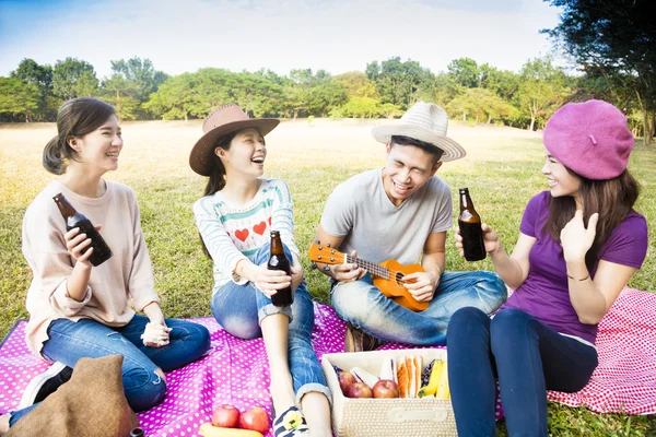 Felici giovani amici godendo picnic e giocare ukulele — Foto Stock