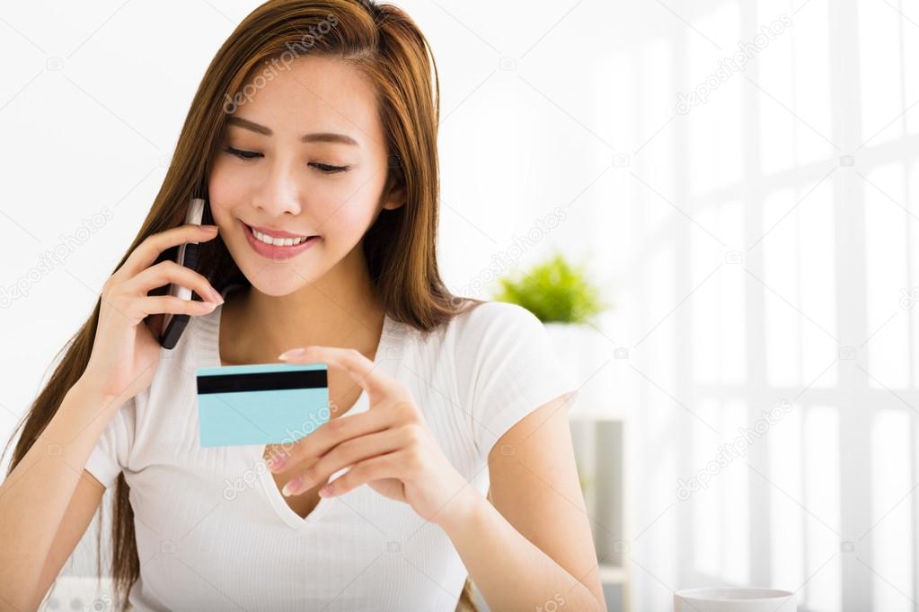 young woman talking on the phone and showing  credit card