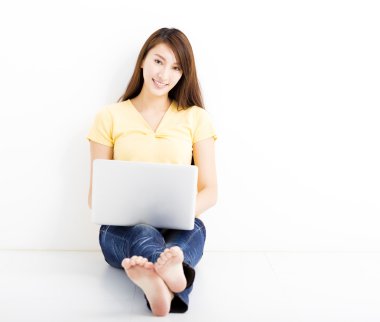 Gülümseyen dizüstü bilgisayar ile genç kadın oturmuş