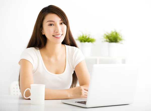 Happy young woman with laptop in living room — Stock Photo, Image