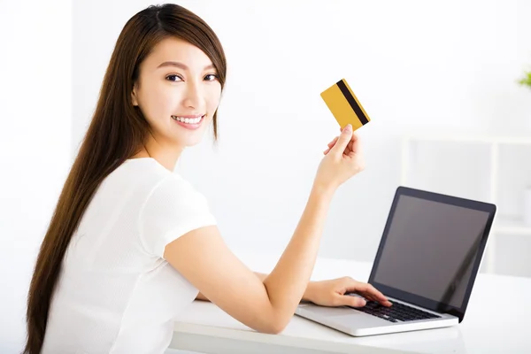 Jovem feliz mostrando cartão de crédito e laptop — Fotografia de Stock