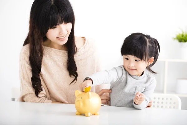 Szczęśliwą matką i córką Wstawianie monety w Piggy bank — Zdjęcie stockowe