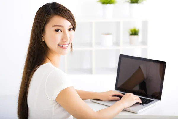Happy young woman with laptop in living room Stock Photo