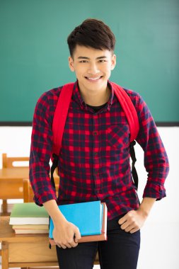 Gülümseyen erkek öğrenci sınıfta ayakta