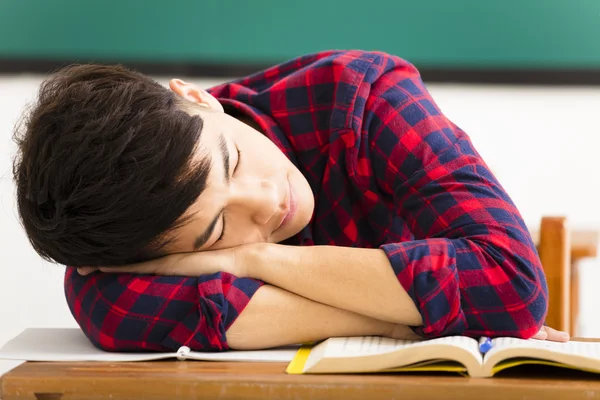 Männliche Schüler schläft auf dem Schreibtisch im Klassenzimmer — Stockfoto