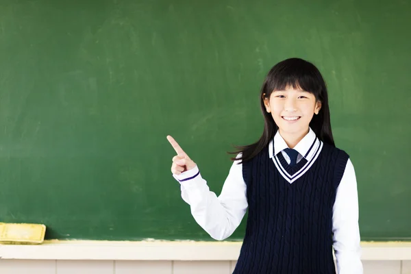 Chica estudiante feliz con gesto de apuntar en el aula —  Fotos de Stock