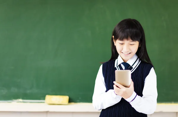 Glückliche Schülerin mit Smartphone im Klassenzimmer — Stockfoto