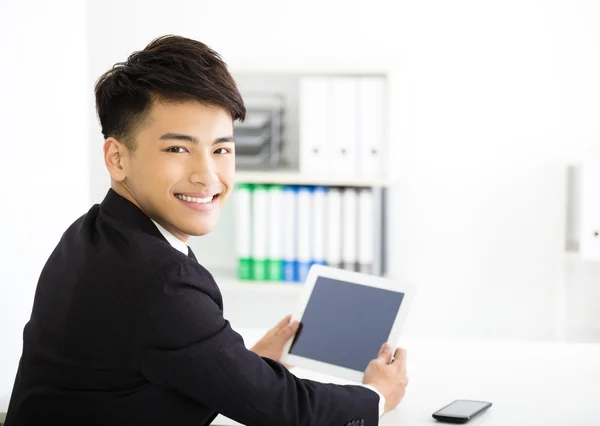 Jovem empresário feliz segurando tablet no escritório — Fotografia de Stock