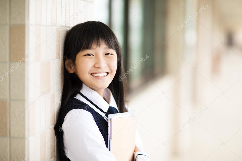 pretty  student girl holding books in front of  classroom