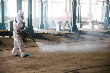 Koruyucu giysili işçiler COVID-19 enfeksiyonundan korunmak için endüstriyel tesisleri, binaları ve iç kısımları kontrol ediyorlar. Salgın hastalık. Coronavirüs