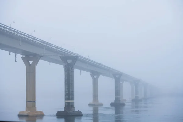 Autumn city landscape. Bridge over the river in heavy fog