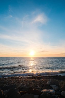 Deniz Burnu. Gün batımında vahşi çakıl taşı plajı. Deniz dalgaları kıyıya vuruyor.