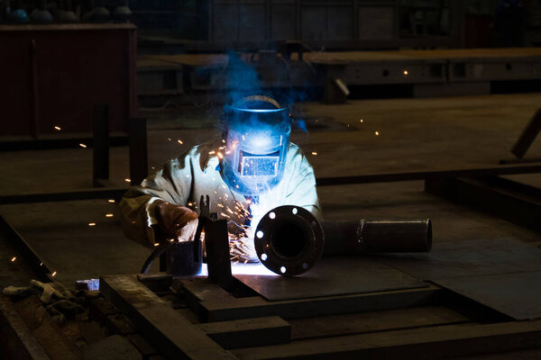 Искры в то время как сварщик использует факел для сварки