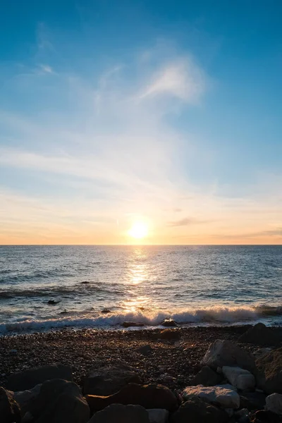 Deniz Burnu. Gün batımında vahşi çakıl taşı plajı. Deniz dalgaları kıyıya vuruyor.