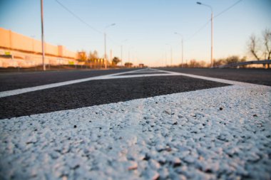 Sokakta asfaltta yol izleri var. Beyaz ayrım çizgisi ve siyah asfalt üzerindeki özel yol işaretleme sembolleri