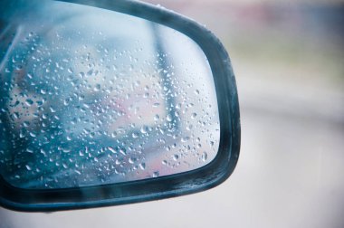 Yağmurlu bir havada araba aynasının yüzeyine düşer.