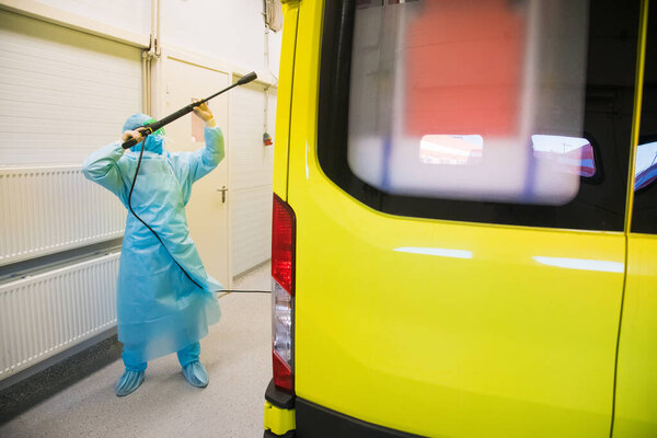 Disinfection of the ambulance. A paramedic treats an ambulance with a disinfectant solution using a spray gun to prevent the spread of the coronavirus (Covid-19)