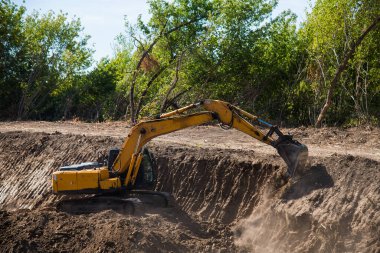 Sürücü kazıcının kovasını toprak işlerini yapmak için kullanır.