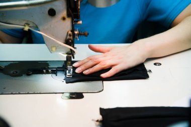 Dikiş makinesinde kadın eli. Ekipmanlarının arkasında çalışan bir terzi. Terzilik süreci, tasarım atölyesi, giyim endüstrisi konsepti