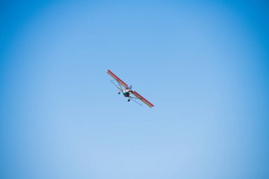 Mavi gökyüzüne karşı küçük bir uçak. Bir tarım havacılık uçağının uçuşu