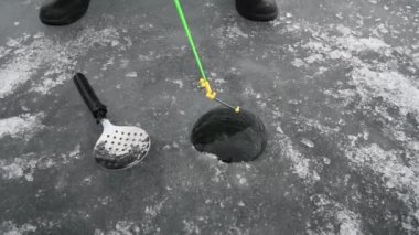 Donmuş gölde kış balıkçılığı. Bir balıkçı donmuş gölün buzunda balık yakalar.