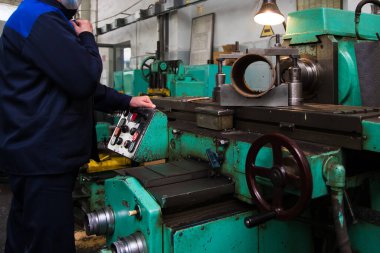 Metal işleme makinesi. Ağır bir sanayi işçisi çelik yapıların üretimi için bir makinede mekanik bir işlem gerçekleştiriyor.
