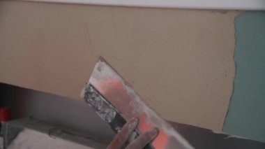 Construction worker with long trowel plastering a wall. Renovation or construction of a house