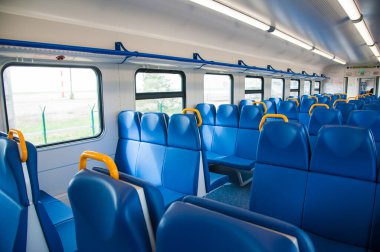 Mavi koltuklu bir tren kulübesinin içinde ve pencereden içeri güneş ışığı giriyor.