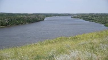 Güzel yaz kırsal doğa manzarası. Mavi nehrin güneşli manzarası ve arka planda ağaçlar olan yeşil çayırlar. Yaz doğasının güzelliği