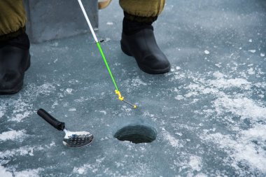Donmuş gölde kış balıkçılığı. Bir balıkçı donmuş gölün buzunda balık yakalar.