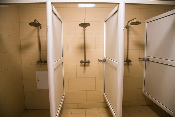 在公共淋浴间用瓷砖和照明洗澡 健身室或游泳池内的普通淋浴 — 图库照片