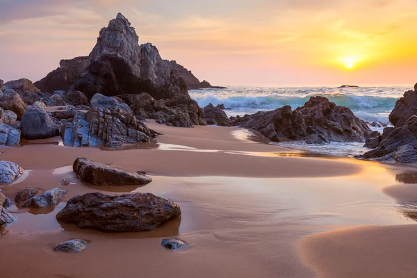 Krajina z velké skály oceán pláž při západu slunce — Stock fotografie